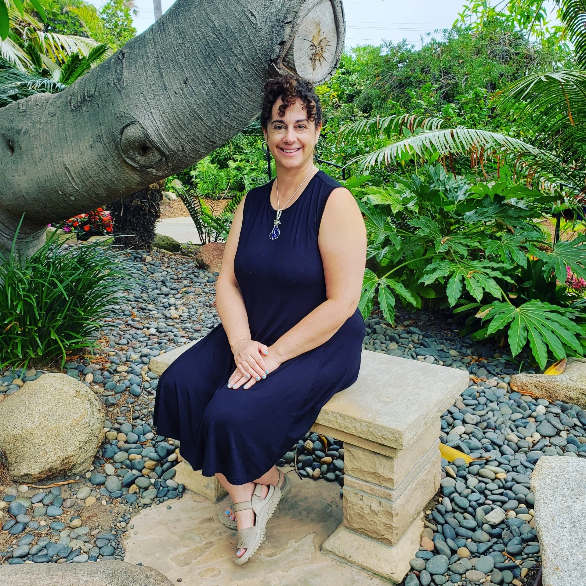 Lily Kandaris sitting on a stone bench in a lush garden